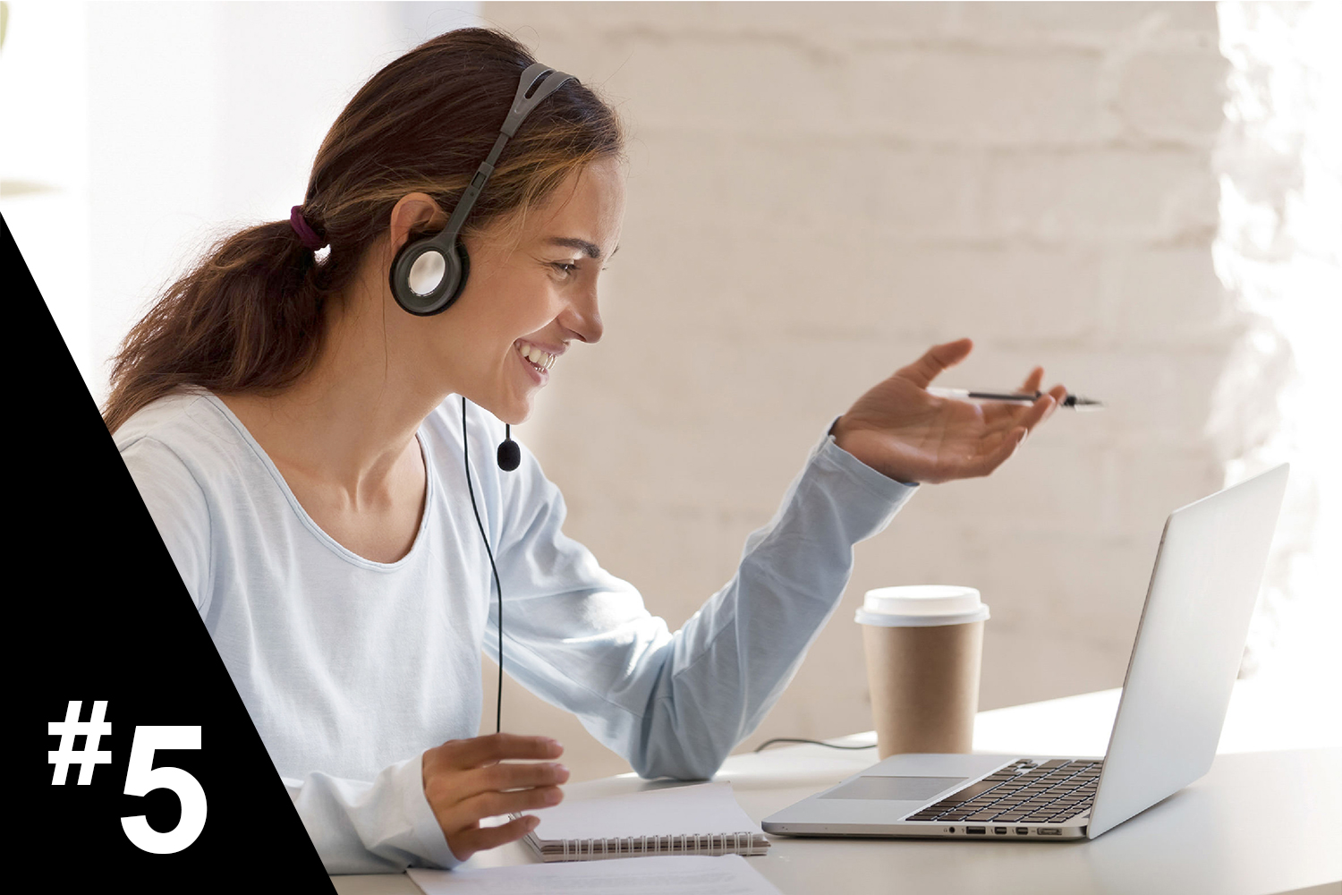 Woman with headphones working from laptop with cup of coffee