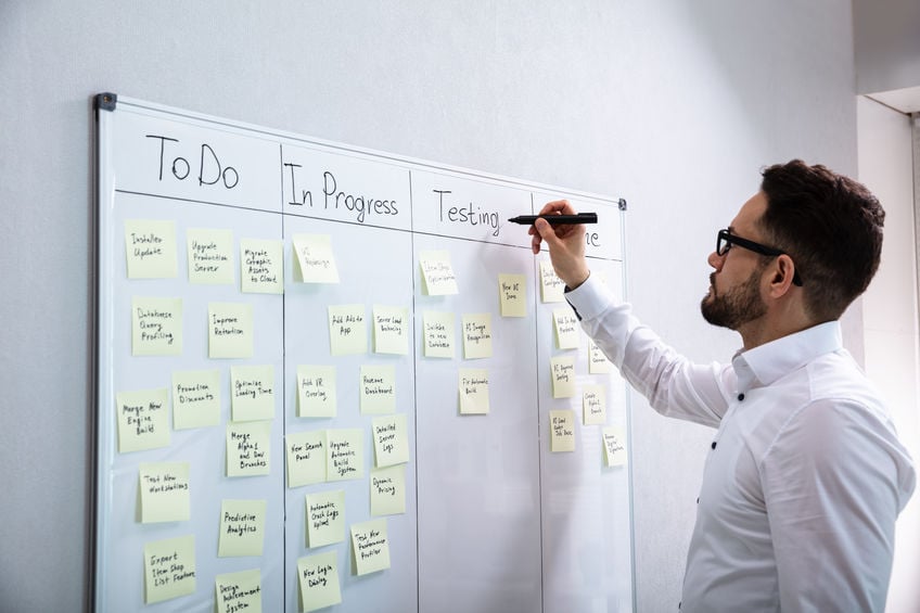 Man writing on Kanban board with marker